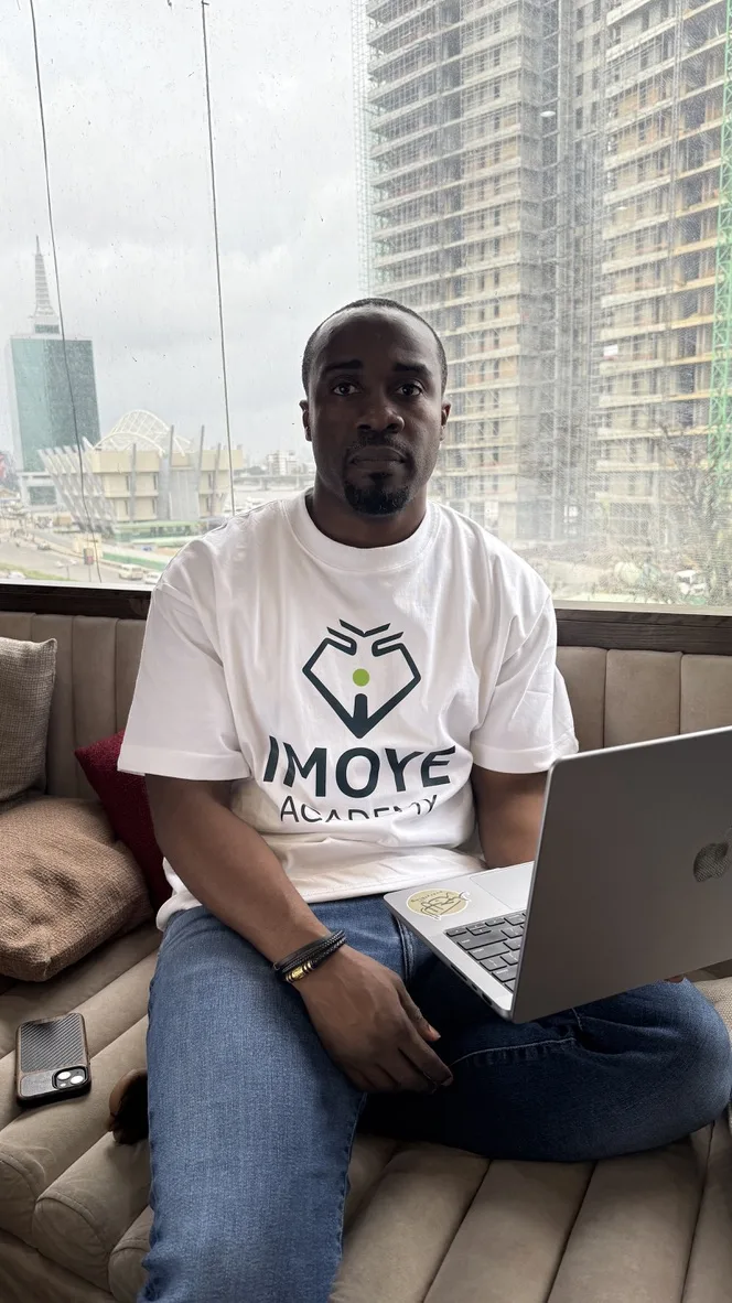 Mo Yusuf in an Imoye Academy shirt, working on a laptop